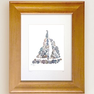 May include: A framed print of a sailboat made from small stones. The sailboat is a light gray color and is set against a white background. The frame is a light brown wood.