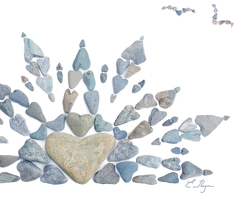 May include: A heart shape made of gray and green stones surrounded by smaller gray heart-shaped stones. The stones are arranged in a radiating pattern on a white background.