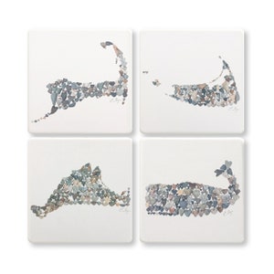 May include: Set of four square coasters featuring a white background with a gray, blue, and brown outline of the island of Martha's Vineyard, Massachusetts, made of small heart-shaped stones.