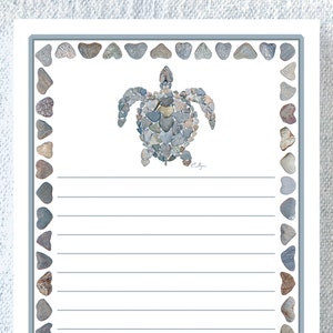 May include: A white lined notepad with a gray border. The border is decorated with a pattern of gray heart-shaped stones. A sea turtle made of gray stones is in the center of the notepad.