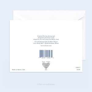 May include: A white card with a blue heart made of heart-shaped rocks. The text on the card reads "love rocks me". The back of the card has a barcode and the text "Original flat-lay photograph designed with heart rocks shaped by the surf along the Maine coast Art and photography by Ellen Thayer Love Rocks Me&reg; South Portland, Maine loverocksme.com".