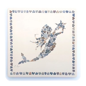 May include: A white ceramic tile with a heart-shaped border. The center of the tile features a mermaid silhouette made of small, colorful stones.