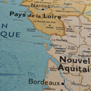 May include: A close-up of a map of France, showing the regions of Pays de la Loire, Nouvelle-Aquitaine, and Poitou-Charentes. The map is printed on light brown paper with blue and green markings. The names of the regions are printed in black.