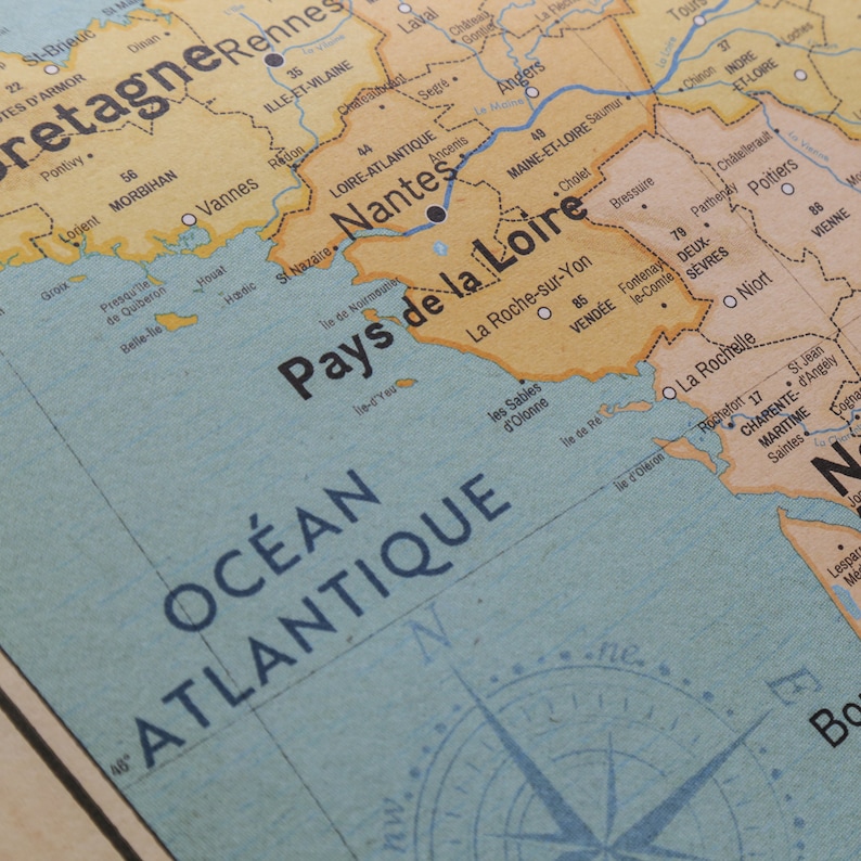 May include: A vintage map of France with the region "Pays de la Loire" highlighted in yellow. The map shows the Atlantic Ocean, the cities of Nantes, La Roche-sur-Yon, and La Rochelle, and the compass rose.