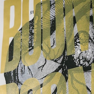 Peut inclure: Un design graphique de couleur or du mot "BOOK" avec une illustration anatomique en noir et blanc d'un cœur superposé sur les lettres.