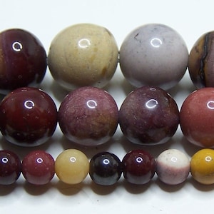 May include: A variety of round, polished gemstone beads in shades of brown, red, purple, and yellow. The beads are arranged in rows from largest to smallest.