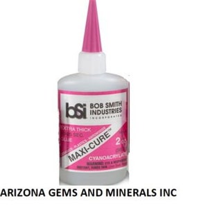 May include: A pink bottle of Bob Smith Industries Maxi-Cure Extra Thick 25 Second Glue. The bottle is labeled with the brand name, product name, and instructions for use. The bottle is 2 oz.