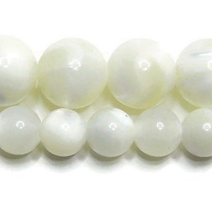 May include: A strand of white mother of pearl beads. The beads are round and have a smooth, polished finish. They are strung on a clear thread.