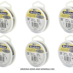 May include: Six spools of Beadalon bead stringing wire in various sizes. Each spool is labeled with the wire's diameter in inches and millimeters, and the length in feet and meters. The spools are white with a clear plastic window showing the silver wire.