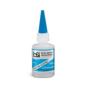 May include: A clear plastic bottle of Insta-Cure super thin cyanoacrylate glue with a blue cap. The bottle is labeled "Bob Smith Industries Incorporated" and "1/2 oz".