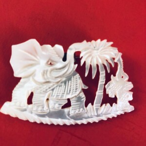 Broche vintage de elefante tallado en nácar fabricado en Taiwán. Muy buen estado con pequeñas piedras de vidrio rojo en los ojos.