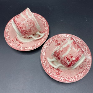 May include: Two vintage teacups and saucers with a pink and white floral pattern. The cups and saucers have a delicate, intricate design.