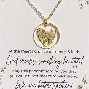May include: A gold-colored necklace with a round pendant. The pendant has a clear resin background with a heart-shaped floral design. The text on the card reads: "God creates something beautiful. We are better together!"