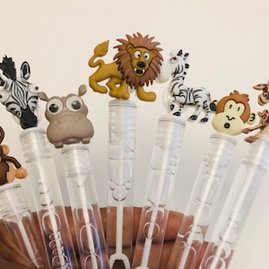 May include: Set of seven colorful plastic bubble wands with animal-shaped tops. The animals include a zebra, a lion, a giraffe, a monkey, a hippopotamus, and two monkeys.