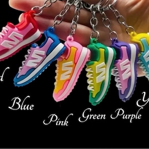 May include: A set of six colorful shoe-shaped keychains. The keychains are red, blue, pink, green, purple, and yellow. Each keychain features a white 'N' logo.