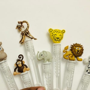 May include: Set of six clear plastic bubble wands with animal-shaped tops. The animals include a giraffe, leopard, lion, elephant, monkey, and zebra. The wands are approximately 6 inches long.