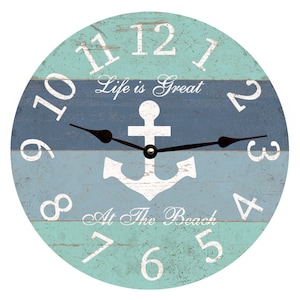 May include: A round wooden clock with a blue and green striped design. The clock face features white numbers, black hands, and a white anchor in the centre. The text "Life is Great At The Beach" is written on the clock face.