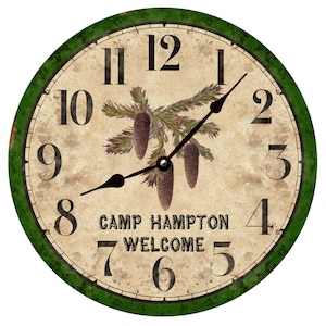 May include: A round, green and cream-colored clock with black hands and Roman numerals. The clock face features a pine branch with pine cones and the text "Camp Hampton Welcome".