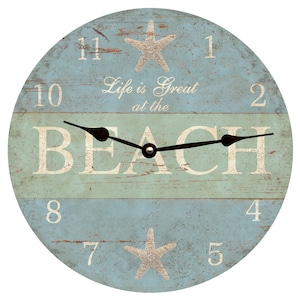 May include: A round wooden clock with a blue and green distressed paint finish. The clock face features the words "Life is Great at the Beach" and two starfish. The clock hands are black.