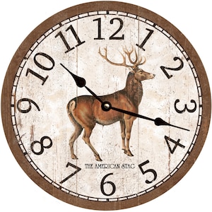 May include: A round wooden clock with a white face and brown trim. The clock features a stag illustration and Roman numeral hour markers. The text "THE AMERICAN STAG" is printed below the stag.