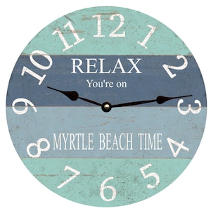 May include: A round wooden clock with blue and green stripes. The clock face has white numbers and the words "RELAX You're on MYRTLE BEACH TIME".