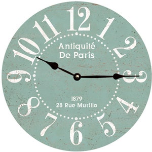 May include: A light blue round clock with white Roman numerals and a black clock hand. The clock face has the text "Antiquité De Paris" and "1879 28 Rue Murillo".