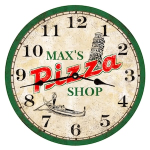 May include: A vintage-style clock with a green border and a white face. The clock features a red and white logo that says "Max's Pizza Shop" with a gondola and the Leaning Tower of Pisa in the background. The clock face has Roman numerals and black hands.