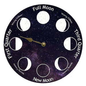 May include: A circular clock face with a black background and white stars. The clock face shows the phases of the moon, with the words "Full Moon", "New Moon", "First Quarter", and "Third Quarter" printed around the edge. A gold-colored hand points to the "Full Moon" phase.