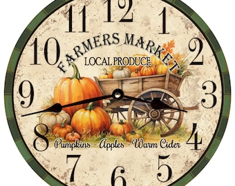 May include: A round, vintage-style clock with a green border and Roman numeral markings. The clock face features a painted image of a wooden wagon filled with pumpkins and the text "Farmers Market Local Produce". The text "Pumpkins - Apples - Warm Cider" is written below the wagon.