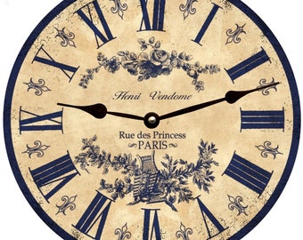 Op de afbeelding: Een vintage-stijl klok met Romeinse cijfers in blauw op een crème achtergrond. De wijzerplaat heeft een bloemmotief met blauwe accenten en de tekst "Henri Vendome Rue des Princess PARIS".