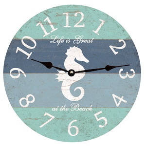 May include: A round wooden clock with a blue and green striped design. The clock features a white seahorse silhouette and the text "Life is Great at the Beach".