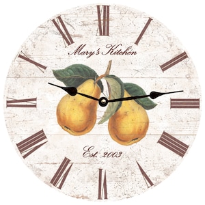 May include: A white round clock with Roman numeral markings and brown hands. The clock face features a vintage-style design with two yellow pears and green leaves. The text "Mary's Kitchen Est. 2003" is printed on the clock face.
