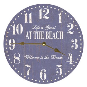 May include: A round purple clock with white numbers and a gold-coloured hour and minute hand. The clock face has the text "Life is Great AT THE BEACH" and "Welcome to the Beach".