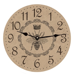 May include: A round, beige-colored clock with black Roman numeral hour markers and black hands. The clock face features a black and white illustration of a bee with a crown above it. The bee is surrounded by a decorative black floral design.