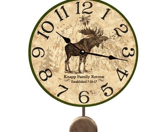 Könnte beinhalten: Eine runde Pendeluhr mit grünem Rahmen und beigefarbenem Zifferblatt. Die Uhr zeigt eine Elch-Illustration und den Text "Knapp Family Retreat Established 7-26-17".