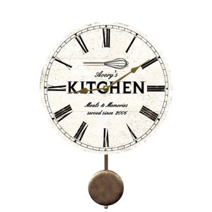May include: White kitchen clock with black Roman numerals and a pendulum. The clock face has the text "Avery's Kitchen Meals & Memories served since 2006" and a whisk.