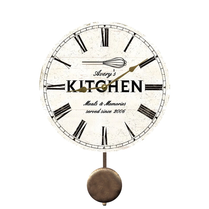 May include: White kitchen clock with black Roman numerals and a pendulum. The clock face has the text "Avery's Kitchen Meals & Memories served since 2006" and a whisk.
