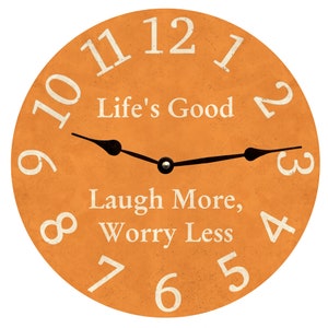 Può includere: Orologio rotondo arancione con lancette nere e numeri bianchi. Il quadrante dell'orologio ha il testo "Life's Good" e "Laugh More, Worry Less".