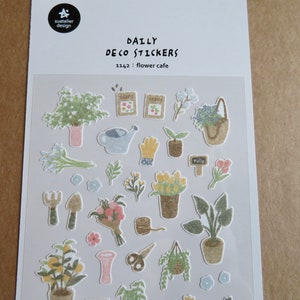 May include: A sheet of "Daily Deco Stickers" with a flower cafe theme. The stickers feature various gardening elements, including potted plants, flowers, gardening tools, and seed packets. The stickers are in soft pastel colors.