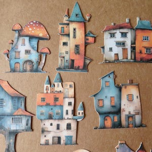 May include: A collection of whimsical, watercolor-style house cutouts in various shapes and sizes. The houses feature vibrant colors like orange, blue, and white, with unique architectural details such as turrets and mushroom-shaped roofs.
