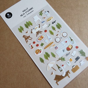 K&ouml;nnte beinhalten: Bogen mit dekorativen Aufklebern zum Thema Picknick. Enth&auml;lt Bilder von Essen, einem Fahrrad, einer Picknickdecke und den Texten "DAILY DECO STICKERS" und "in the garden". Die Aufkleber sind in verschiedenen Farben gehalten.