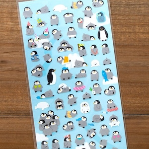 May include: A sheet of penguin stickers in various poses and outfits. The stickers feature penguins in different colors, including gray, white, and black, with some wearing hats, scarves, and holding fish. The background is a light blue.