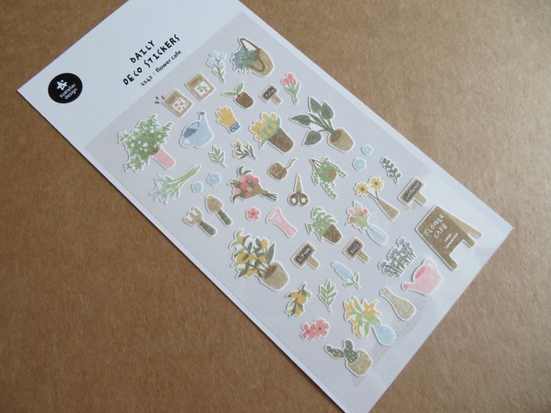 May include: A sheet of "Daily Deco Stickers" featuring various floral and gardening-themed illustrations. The stickers include potted plants, bouquets, gardening tools, and the text "Flower Cafe". The stickers are in soft pastel colors.