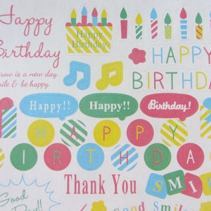以下が含まれることがあります： カラフルな誕生日のテーマのステッカーシート。 「Happy Birthday」、「Thank You」、「Smile」などのテキストが含まれています。ケーキ、ろうそく、音符、ギフトボックス、そして「Happy!!」と「Birthday!」の吹き出しの画像が特徴です。