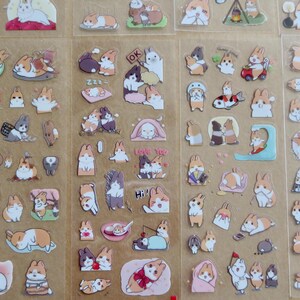 May include: Sheets of clear stickers featuring various cartoon rabbits in different poses and settings. The stickers showcase rabbits in various colors, including white, brown, and gray, with some wearing accessories or interacting with objects.