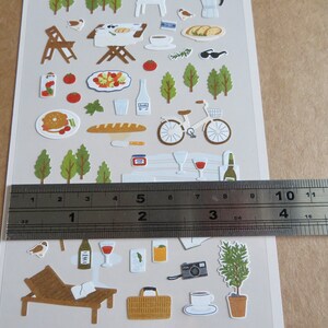 K&ouml;nnte beinhalten: Ein Bogen dekorativer Aufkleber mit Picknick- und Freizeit-Themen im Freien. Enth&auml;lt Illustrationen von Essen, Getr&auml;nken, einem Fahrrad, B&auml;umen und einer Liege. Die Aufkleber sind etwa 10 cm breit.