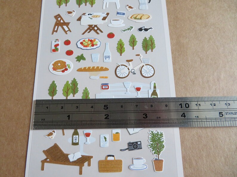 K&ouml;nnte beinhalten: Ein Bogen dekorativer Aufkleber mit Picknick- und Freizeit-Themen im Freien. Enth&auml;lt Illustrationen von Essen, Getr&auml;nken, einem Fahrrad, B&auml;umen und einer Liege. Die Aufkleber sind etwa 10 cm breit.