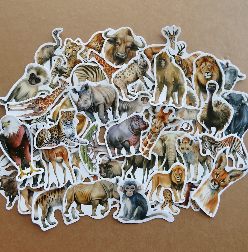 May include: A selection of animal stickers depicting African wildlife. The stickers include a giraffe, lion, zebra, rhino, elephant, and other animals. The stickers have a white border and are arranged on a brown surface.