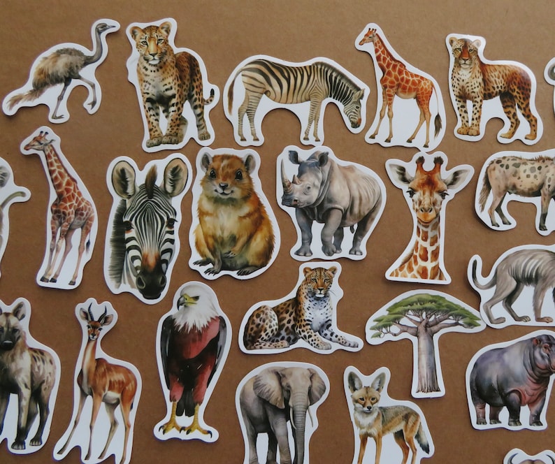 May include: A selection of animal stickers depicting African wildlife. The stickers showcase a giraffe, zebra, leopard, rhino, elephant, and other animals. Each sticker is a detailed watercolour illustration with a white border, set against a brown background.
