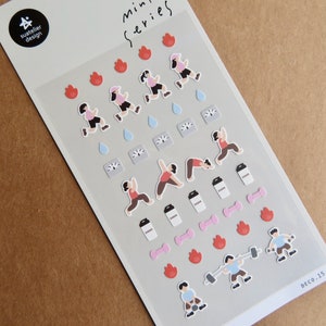 May include: A sheet of mini series stickers featuring fitness-themed illustrations. The stickers depict running figures, yoga poses, dumbbells, coffee cups, and flame icons. The stickers are on a grey background with the text "DECO.15".